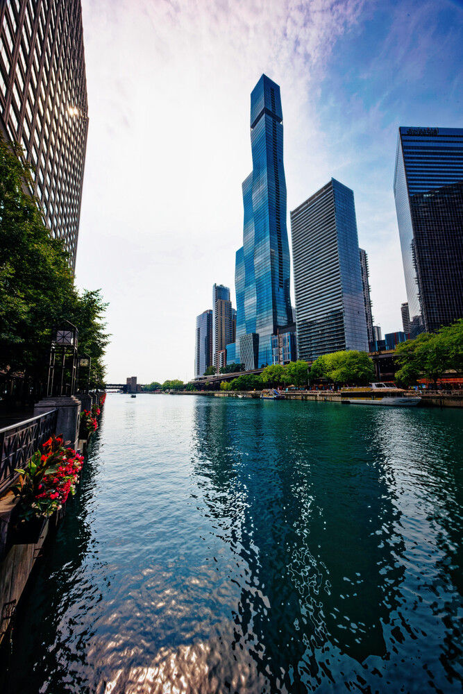 Chicago skyline with blue glass tower reflected in calm river waters