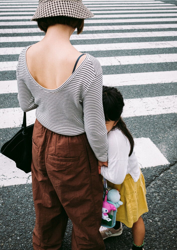Adult and child holding hands while crossing a zebra crossing