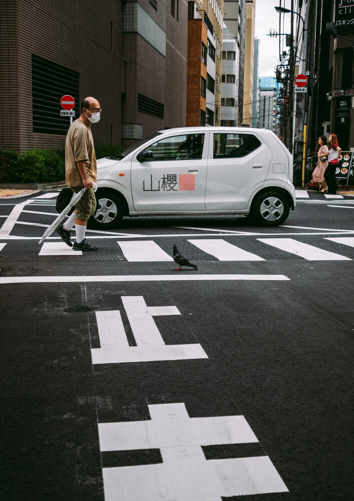 Pedestrian crossing street with white taxi car and geometric crosswalk markings