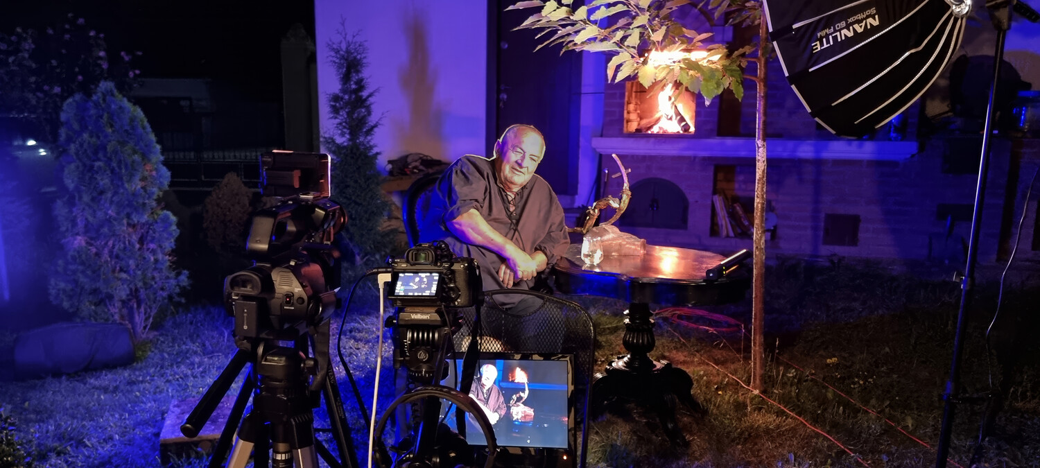 Filmmaker operating camera on tripod during nighttime production shoot with professional lighting setup