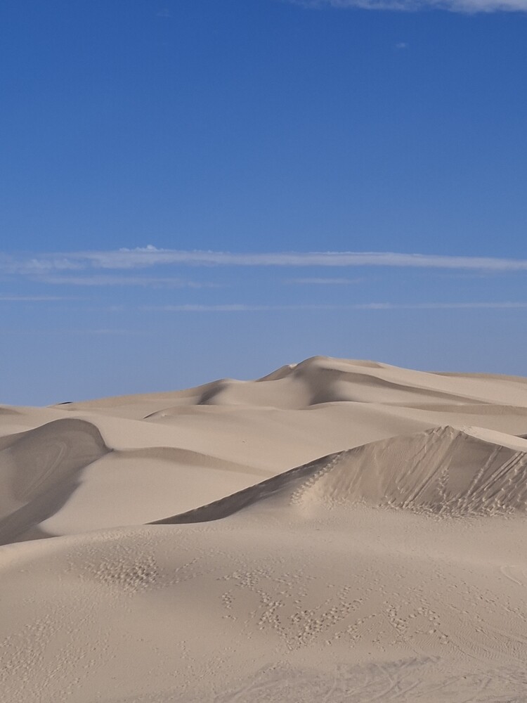 Sand dunes with rippled texture under clear blue sky