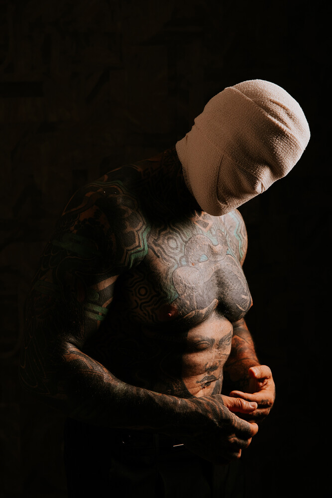 Shirtless male figure with tilted head and closed eyes, dramatic side lighting against black background