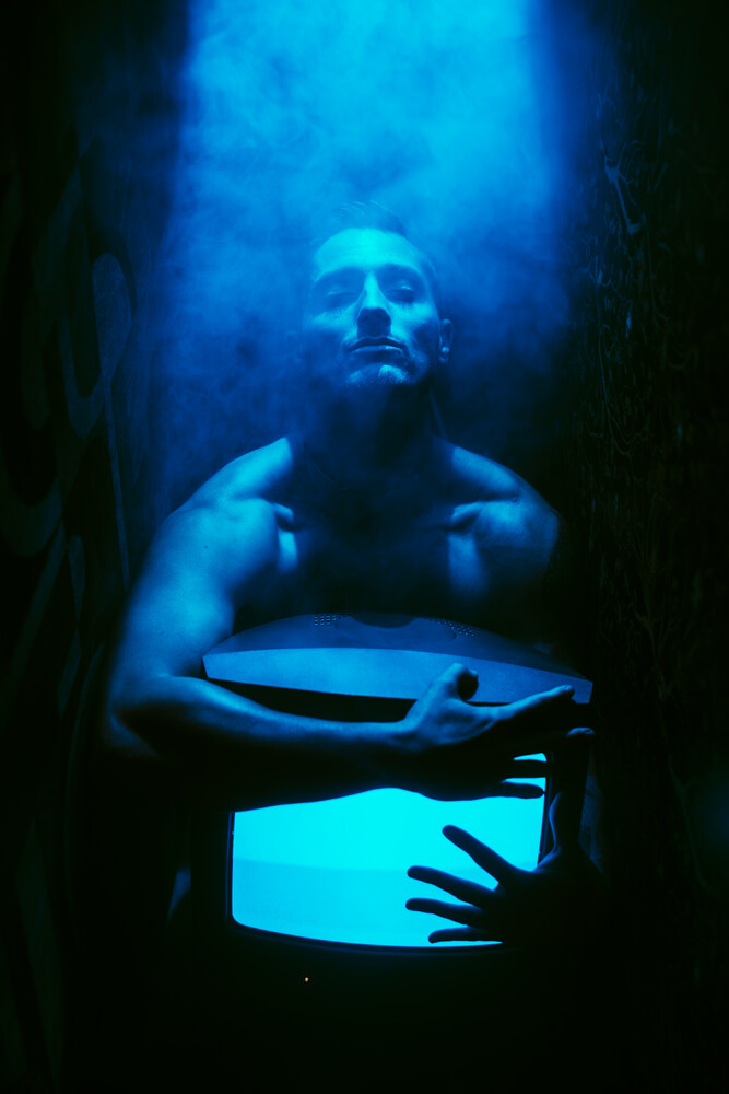 Shirtless man with glowing blue light emanating from tablet device he holds