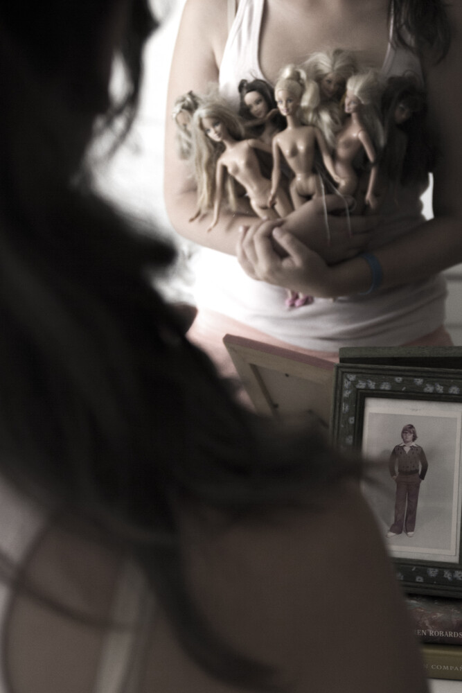 Designer examining clay sculptural figures on garment with design reference on tablet