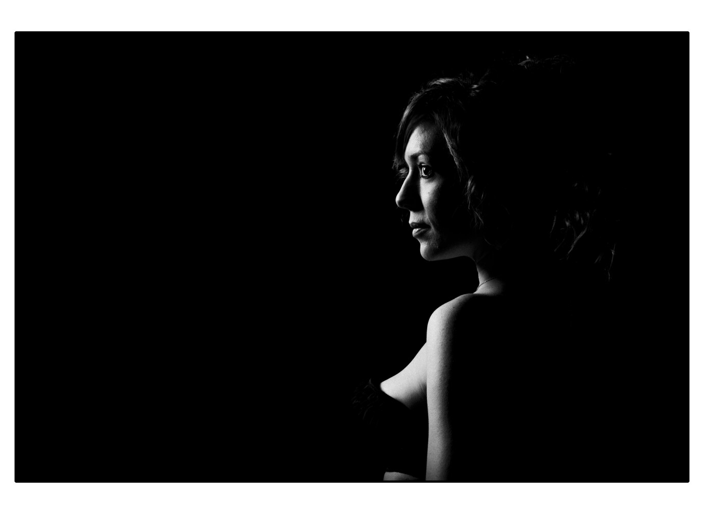 Profile silhouette of a woman lit by dramatic side lighting against a black background