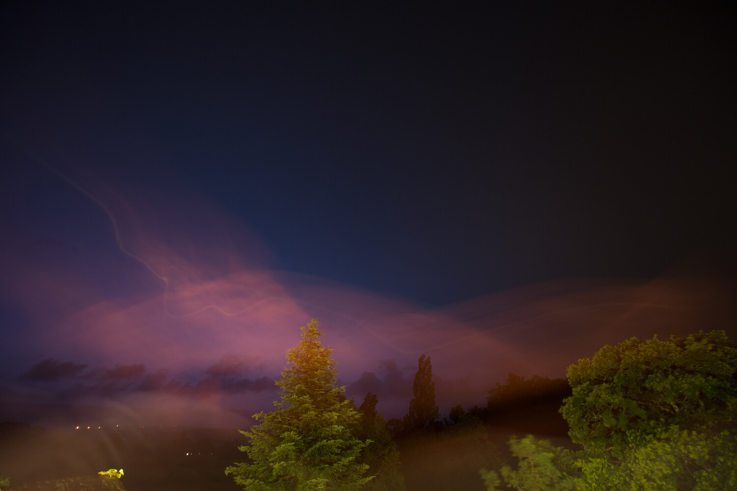 Dramatic twilight sky with purple and pink clouds over silhouetted evergreen trees