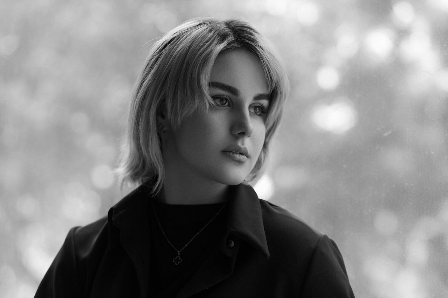 Woman with shoulder-length blonde hair in black and white portrait against bokeh background