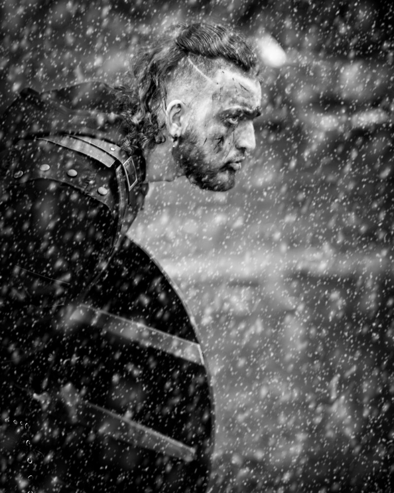 Man in profile looking over shoulder in heavy rain, black and white portrait