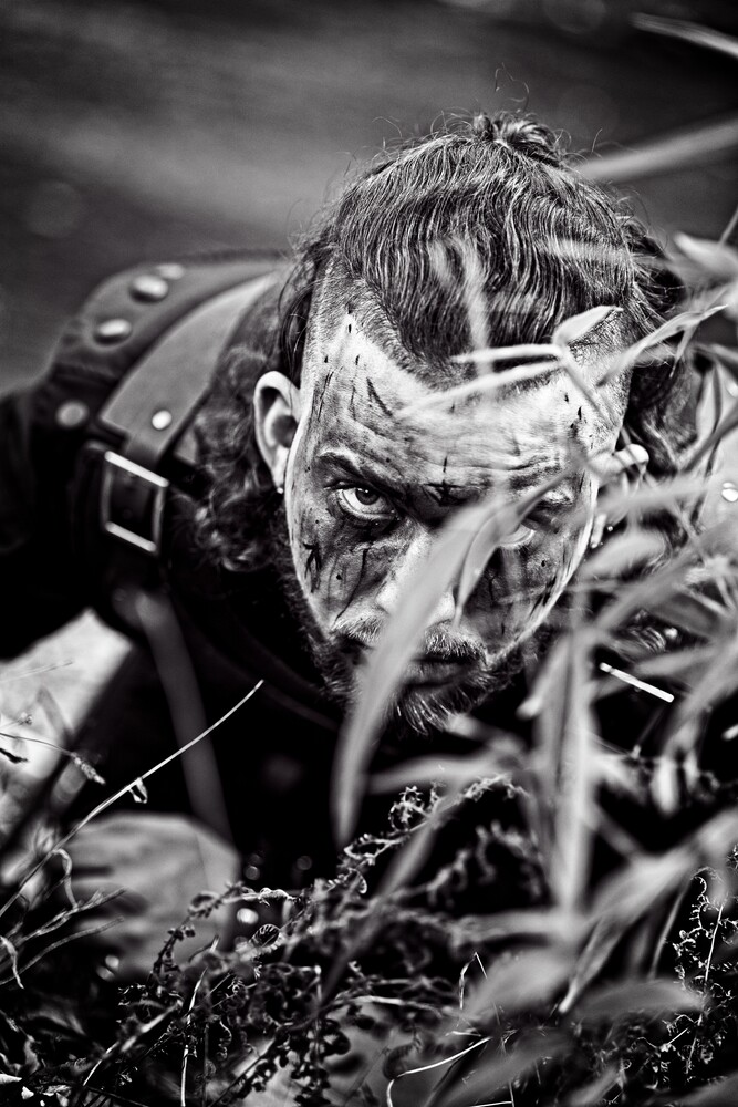 Person covered in water and mud, face forward with intense expression in black and white