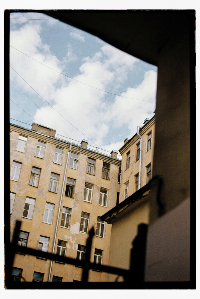 Upward view of yellow residential buildings framing a cloudy sky