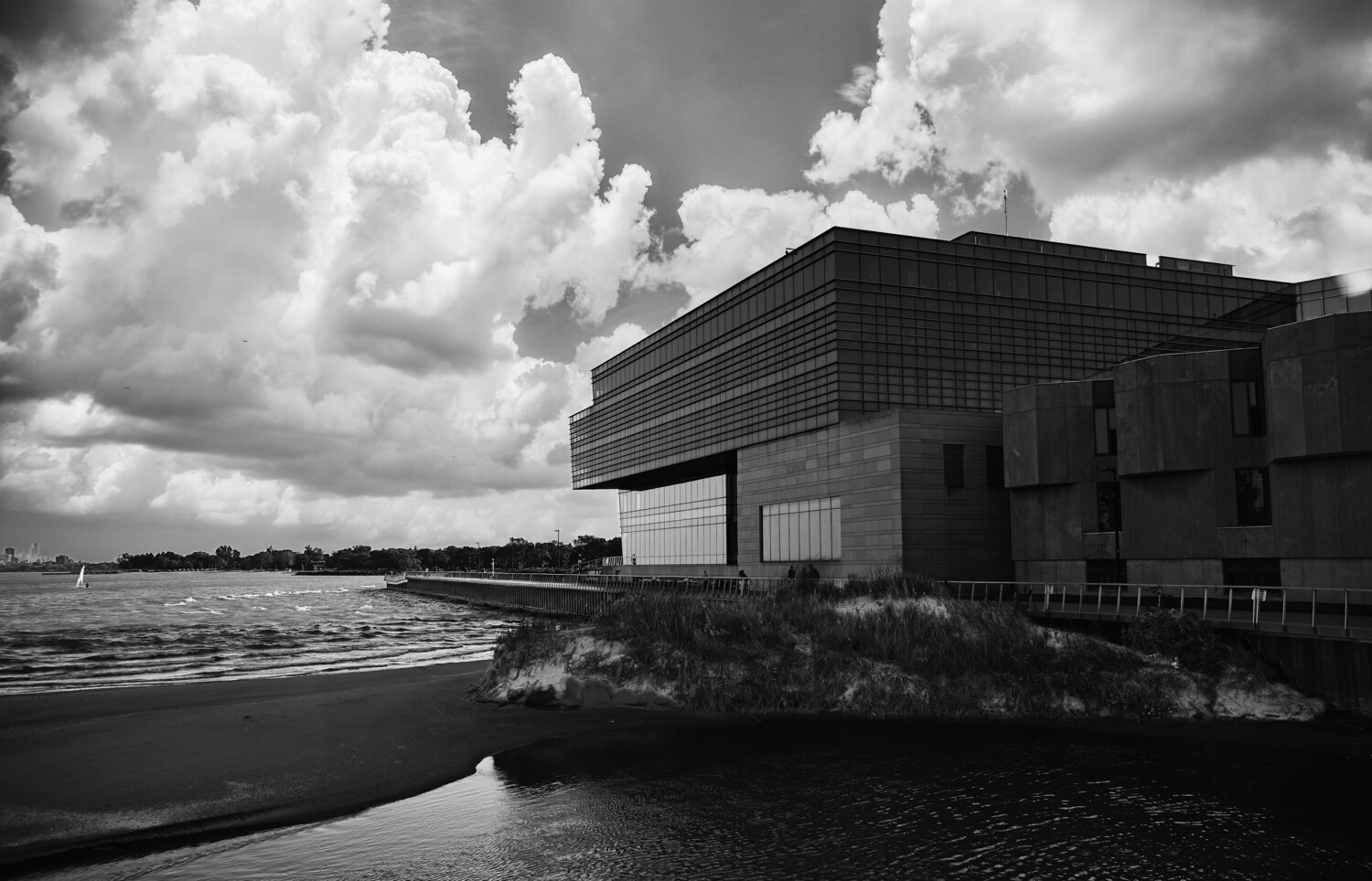 Modern industrial building beside calm water under dramatic cloudy sky