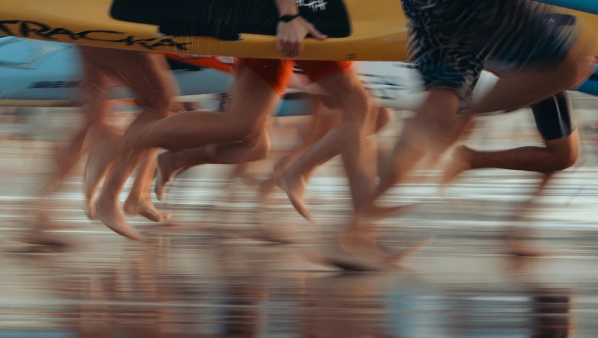 Multiple people running on wet sand with motion blur capturing dynamic movement and speed.