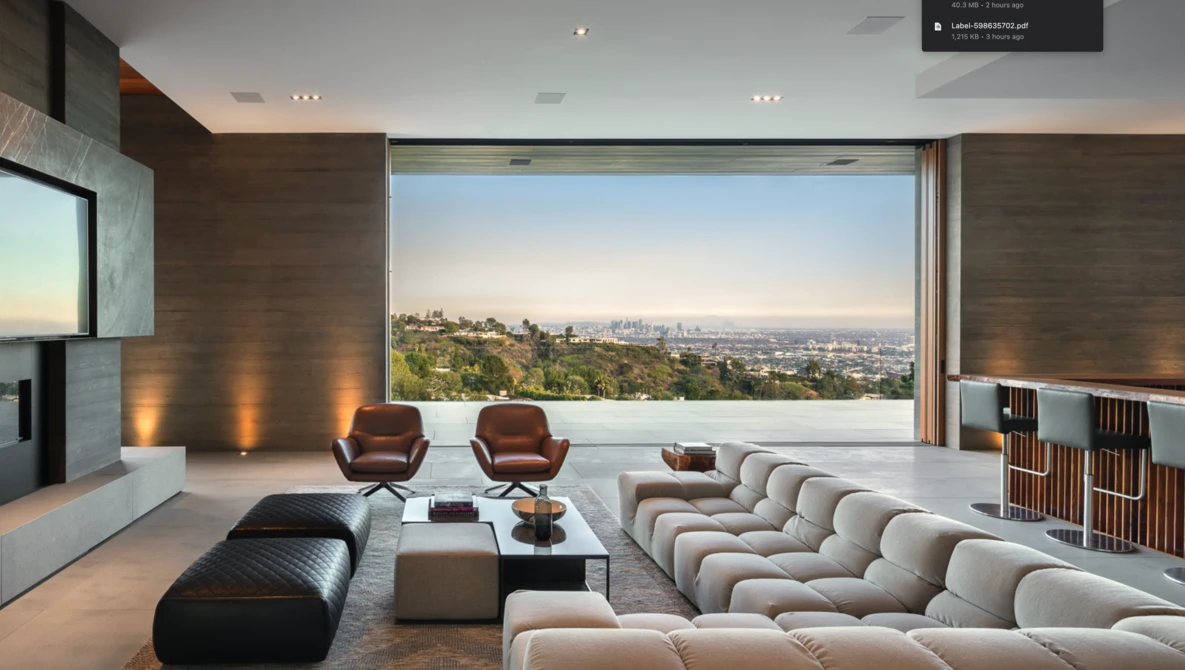 Modern living room with panoramic city view through floor-to-ceiling windows, featuring sculptural furniture and minimalist décor.