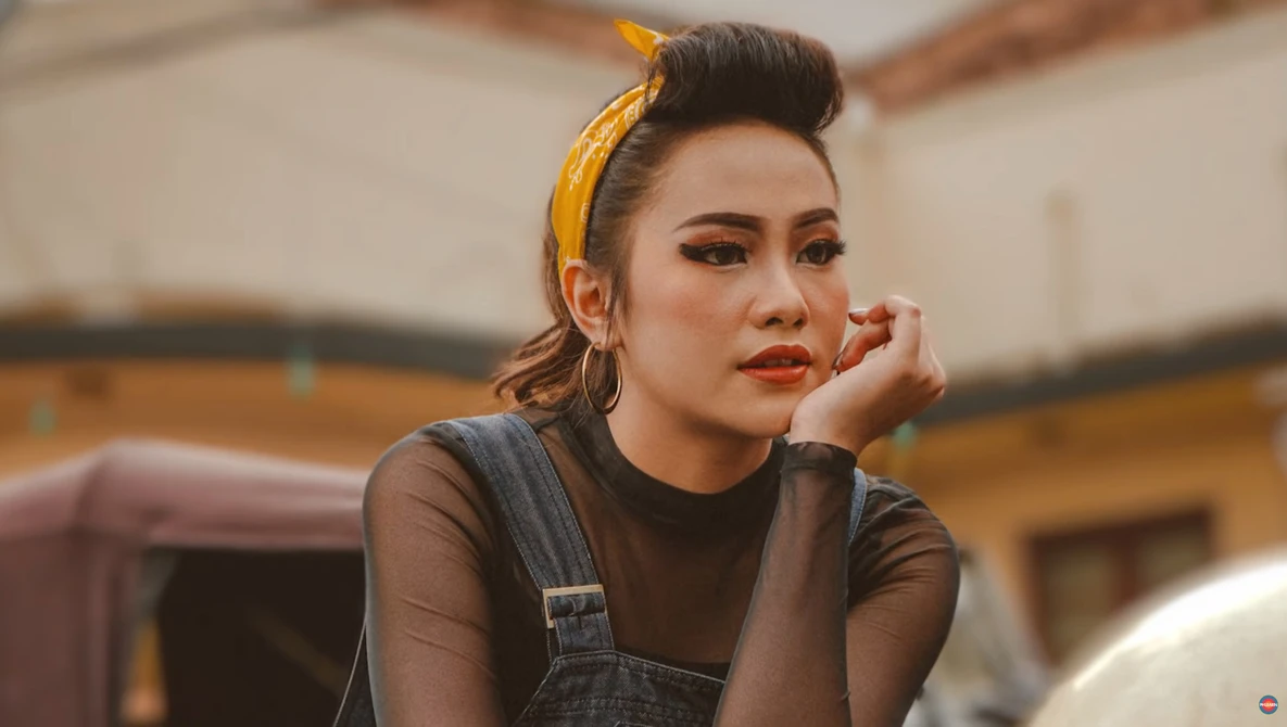 Woman with styled hair and warm makeup looking thoughtfully to the side in golden hour light.