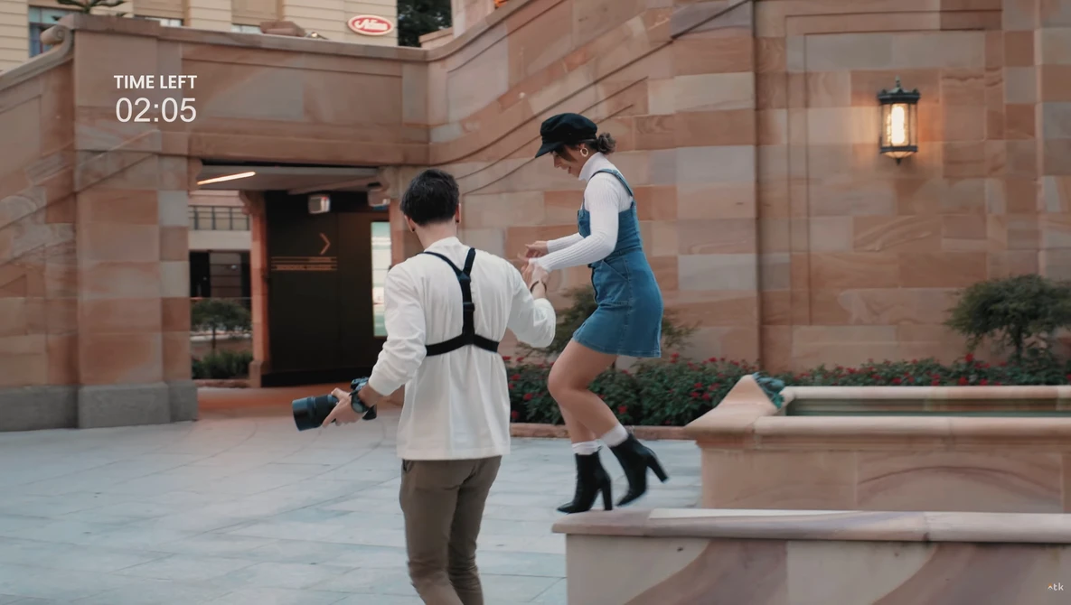 Two people jumping in an urban courtyard with a 2:05 countdown timer overlay.
