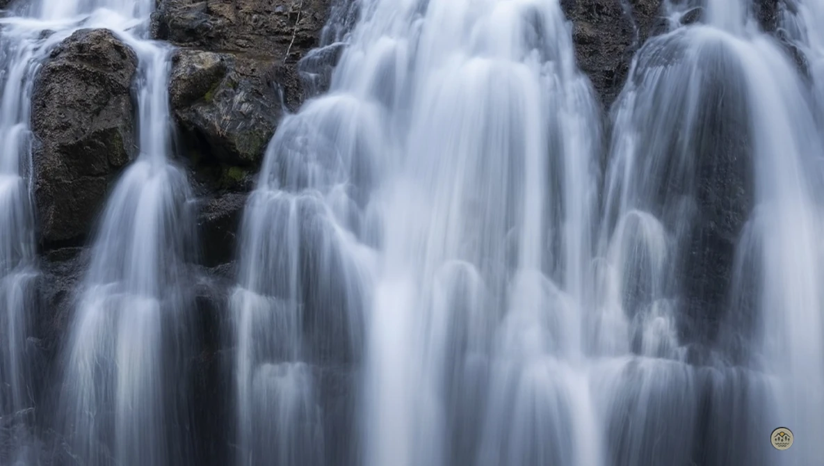 Cascading waterfall flowing over dark rocky terrain with silky water motion blur effect.