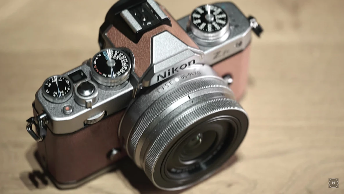 Nikon rangefinder camera with chrome and brown leather body, vintage lens attached, viewed from above on a neutral surface.