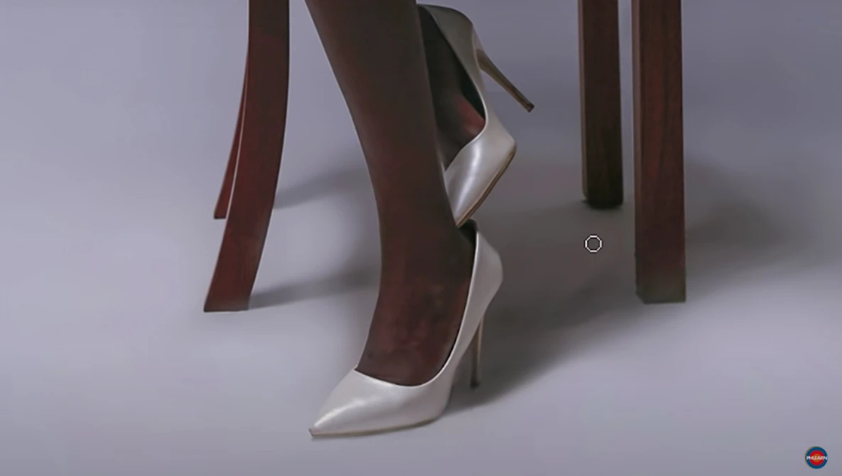 3D rendered product shot of a white pointed-toe stiletto heel shoe positioned among brown fabric ribbons against a light gray backdrop.