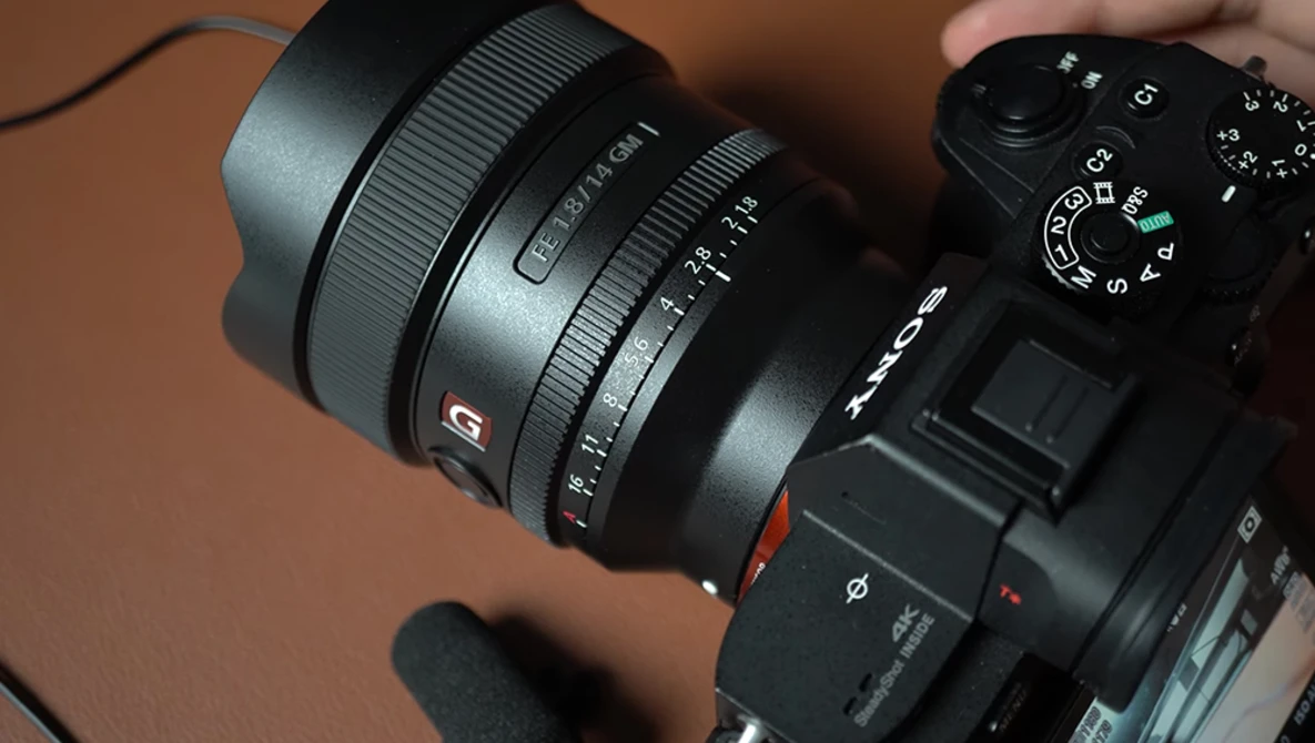 Sony mirrorless camera with wide-angle zoom lens attached, shown against a brown background.