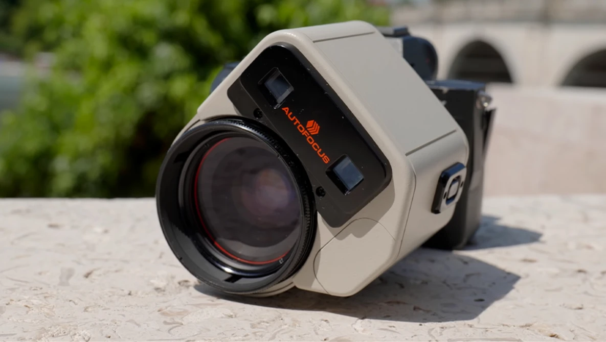 Vintage thermal imaging camera with cream-colored body and black lens on stone surface.
