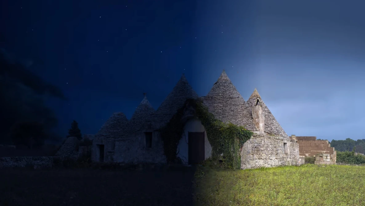 Stone ruins of a small church or chapel with peaked roof silhouetted against twilight sky.