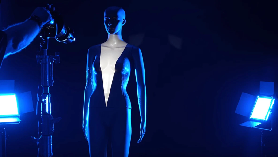 Fashion mannequin lit by blue LED panels in a dark studio with professional lighting setup.