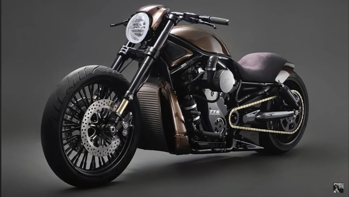 Custom cruiser motorcycle with extended fork, chrome headlight, and wide whitewall tires on neutral background.