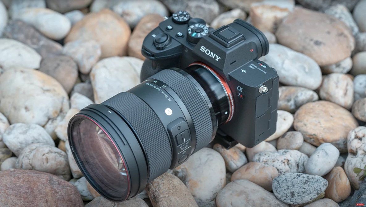 Sony mirrorless camera with sigma lens on rocky ground.