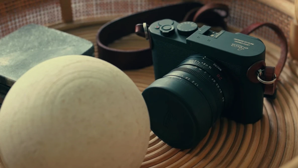 Rangefinder camera with lens and accessories arranged on a wooden surface.