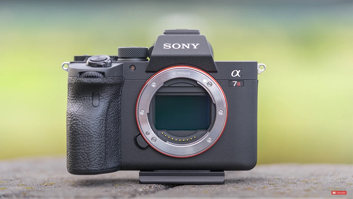 Sony α7 III mirrorless camera body with open mirror box, displayed against a blurred yellow-green background.