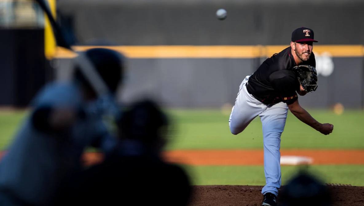 Pitcher mid-delivery throwing a baseball from the mound, captured with selective focus on the athlete.