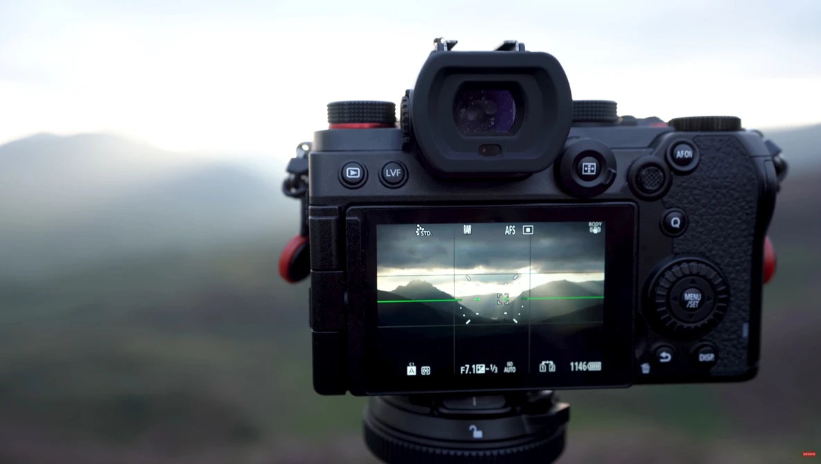 Mirrorless camera mounted on tripod displaying live view histogram and exposure data on rear LCD screen.