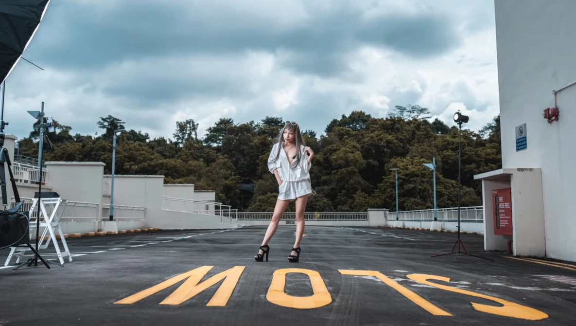 Woman in white shirt posing on rooftop with yellow crosswalk markings painted on asphalt.