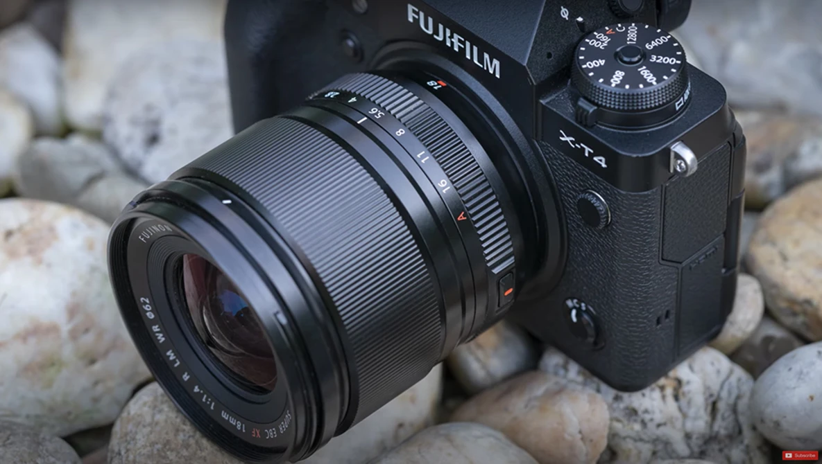Fujifilm camera with attached lens resting on rocky surface outdoors.