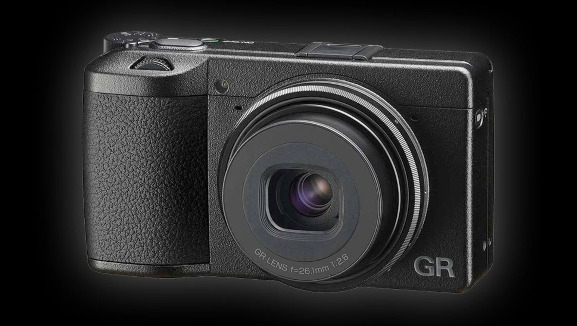 Ricoh GR compact digital camera with fixed lens displayed against dark background.