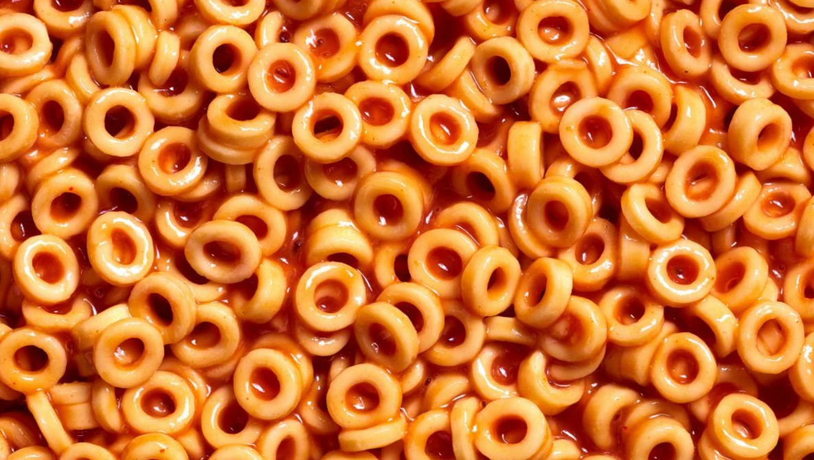 Overhead view of golden breakfast cereal rings with holes, densely packed and filling the entire frame.