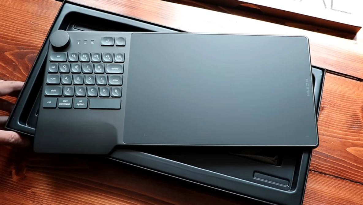 Portable keyboard with touchpad resting on wooden desk surface.