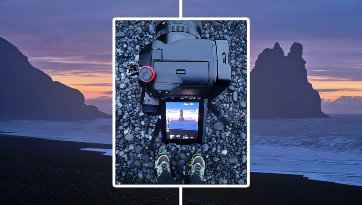 Camera mounted on pebbles displaying a landscape scene on its screen, framed against a coastal sunset.