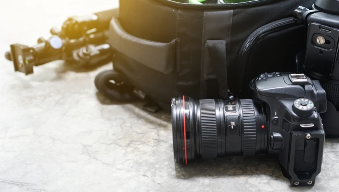 Professional DSLR camera with wide-angle lens on marble surface next to camera bag.