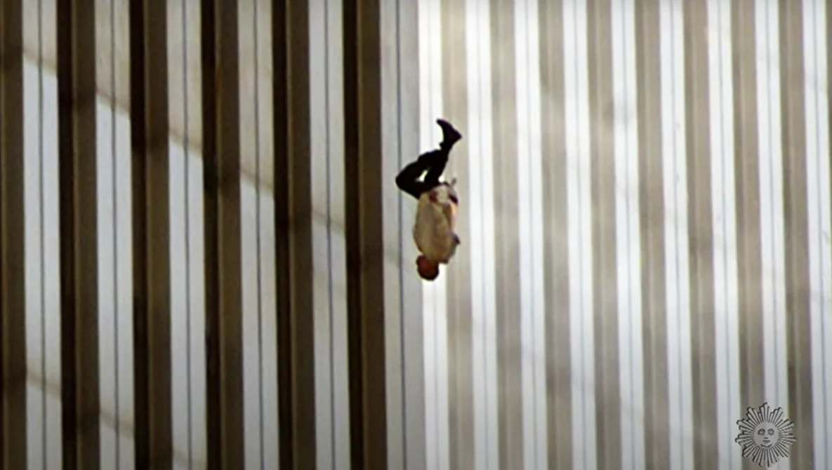 Person in dark clothing suspended mid-fall against vertical striped background.
