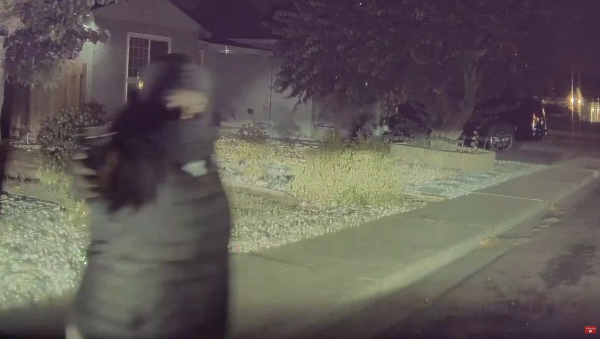 Blurred figure in motion on a nighttime residential street with thermal or infrared color grading.