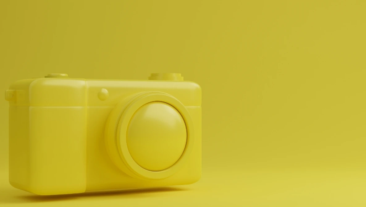 Monochromatic yellow toy camera against a solid yellow background.