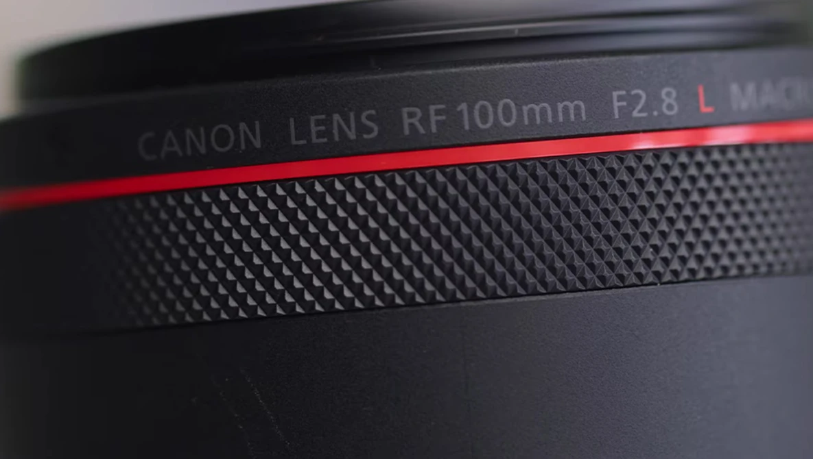 Canon RF 100mm F2.8 L macro lens barrel with red accent stripe and textured grip surface.