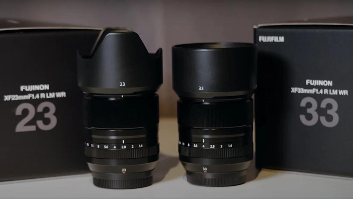 Two Fujifilm XF prime lenses with hoods displayed alongside their original boxes.