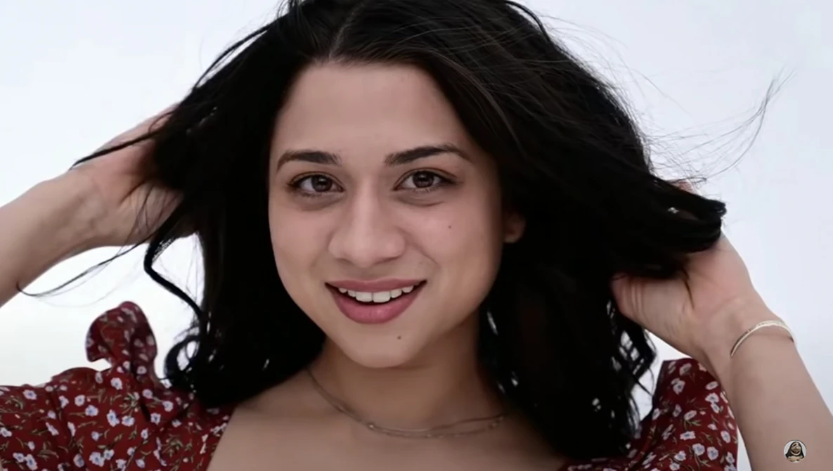 Young woman with long black hair smiling at camera against white background.