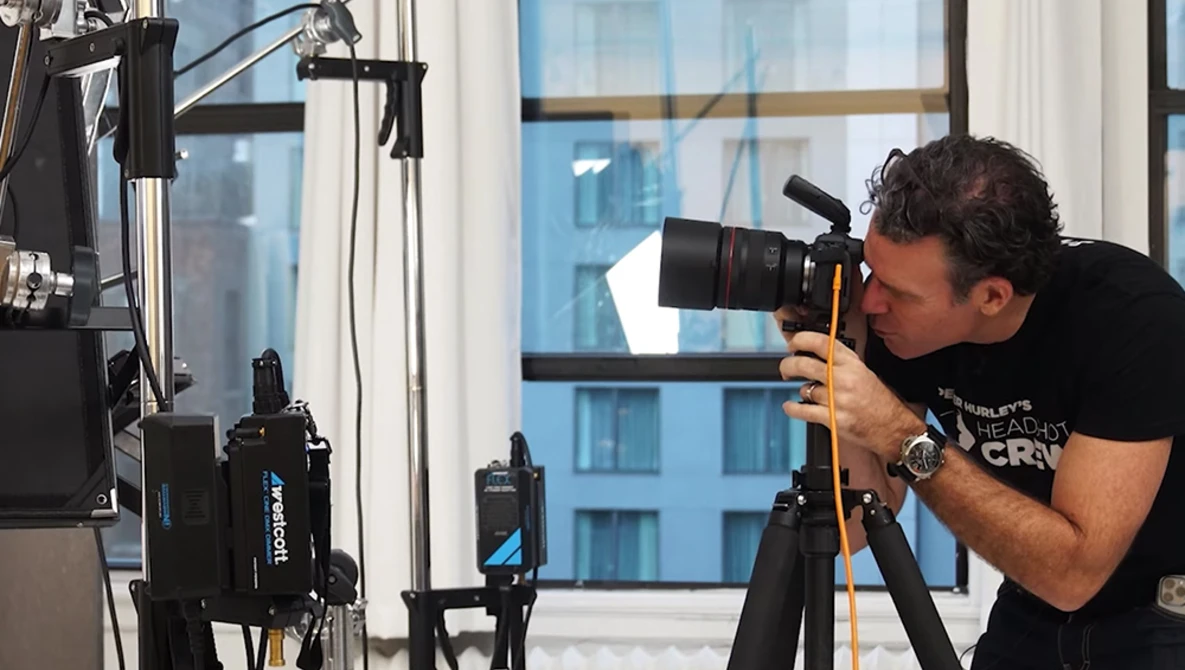 Cameraman operating a professional video camera on a tripod in a high-rise interior.