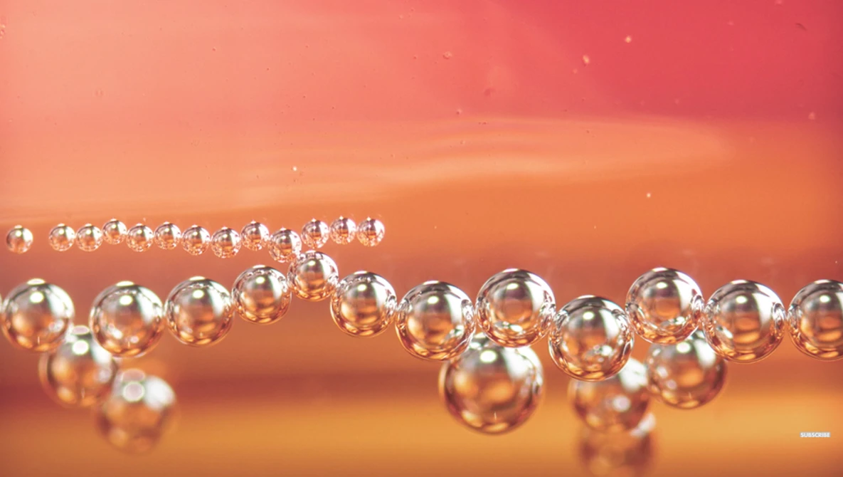 Water droplets arranged in curved lines against a warm orange and red gradient background.