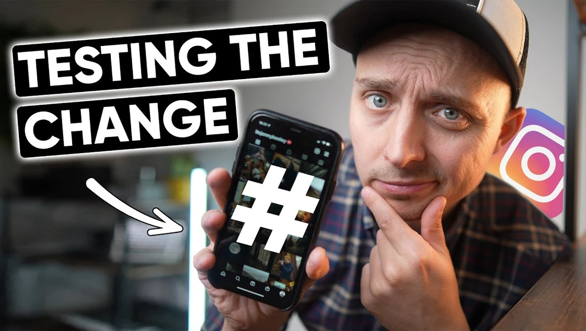 Person holding a smartphone with a hashtag symbol displayed on screen, with text overlay reading 'TESTING THE CHANGE'.