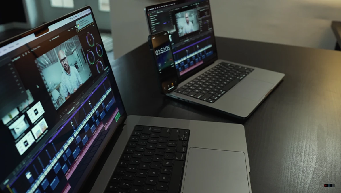 Video editing workstation with multiple monitors displaying timeline and color correction software.