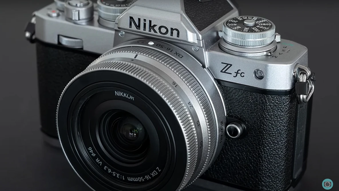 Nikon Z fc mirrorless camera with attached lens, shown against a neutral gray background.